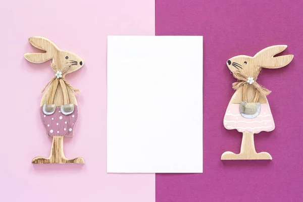 Романтическая композиция Пара деревянных влюбленных фигурки кроликов и белая открытка для текста на розовом фиолетовом фоне Концепция валентинки — стоковое фото