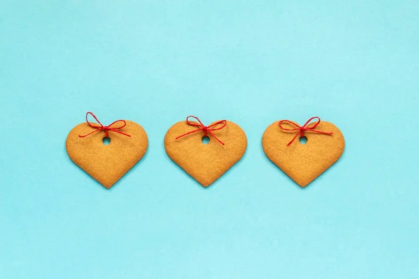 Biscoitos de gengibre em forma de coração decorados com um arco no fundo azul. Vista superior Copiar espaço cartão Valentine — Fotografia de Stock