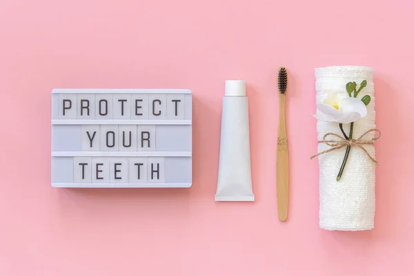 Proteggi il testo dei denti sulla scatola chiara e sulla spazzola di bambù ecologica naturale per denti, asciugamano, tubo di dentifricio. Set per il lavaggio su sfondo rosa. Concetto di assistenza sanitaria dentale Vista dall'alto — Foto Stock