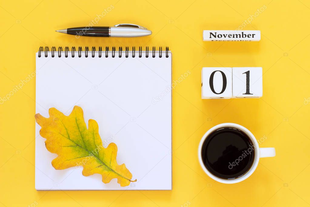 calendar November 1 cup of coffee, notepad with pen and yellow leaf on yellow background