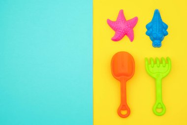 Mavi sarı arka planda kopya alanı ile Sandbox veya kumlu plajda yaz oyunları için çok renkli set çocuk oyuncakları. Üst görünüm Flat Lay konsept. Metin veya tasarım için şablon