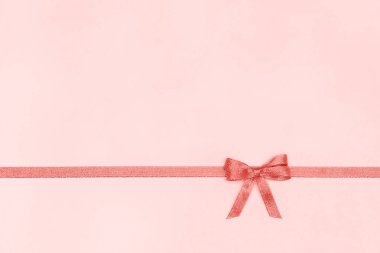 Metin için kopya alanı ile pastel pembe arka plan üzerinde yay ile dekoratif parlak kurdele, mercan tonlu Üst görünüm, Şablon