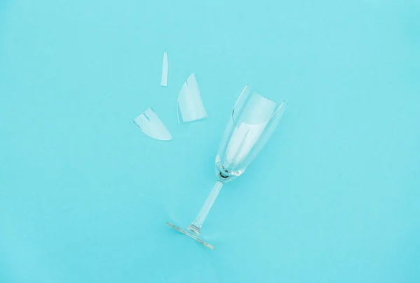 Σπασμένο ποτήρι σαμπάνιας με θραύσματα σε μπλε φόντο με χώρο αντιγραφής. Έννοια καταπολέμηση του αλκοολισμού, μέθη και άρνηση του οινοπνεύματος. Δημιουργική επάνω όψη επίπεδη Lay — Φωτογραφία Αρχείου