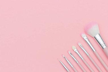 Pastel pembe arka plan üzerinde pembe makyaj fırçaları seti