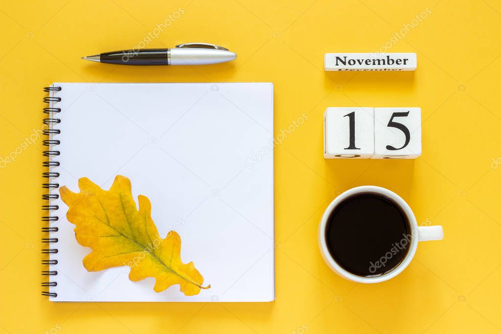 calendar November 15 cup of coffee, notepad with pen and yellow leaf on yellow background