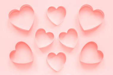 Pastel pembe arka plan üzerinde kalp şeklinde pembe kesiciler çerezleri, colar tonda. Aşk romantik desen, şablon