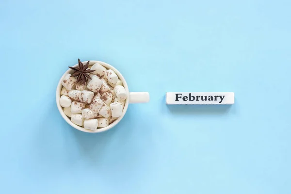 Xícara de cacau marshmallows e calendário fevereiro no fundo azul — Fotografia de Stock