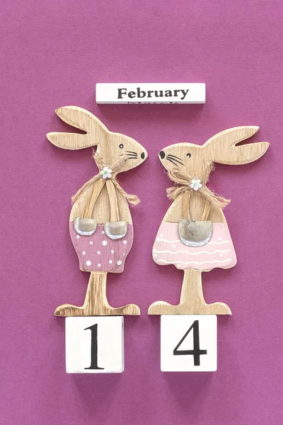 Composición romántica Calendario de cubos de madera 14 de febrero y par de amantes de la madera conejos figurados sobre fondo púrpura. Concepto tarjeta de San Valentín. Vista superior Flat Lay —  Fotos de Stock