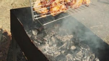 Mans el ızgara üzerinde barbekü döner. Izgarada tavuk kanadı kızartın, kapatın. Piknikte güneşli bir yaz gününde barbekü pişirme