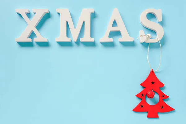 Texto Xmas de letras brancas e vermelho Natal decoração árvore brinquedo no fundo azul, espaço de cópia. Concepção Feliz Natal. Estilo mínimo Visão superior Modelo de leigos planos para o seu design, cartão, convite — Fotografia de Stock