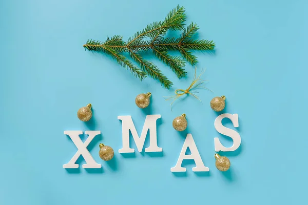 휴일 구성. 파란색 배경에 흰색 문자, 녹색 전나무 가지와 크리스마스 장식 황금 공에서 텍스트 크리스마스. 개념 메리 크리스마스입니다. 탑뷰 플랫 레이 인사말 카드, 초대장 — 스톡 사진