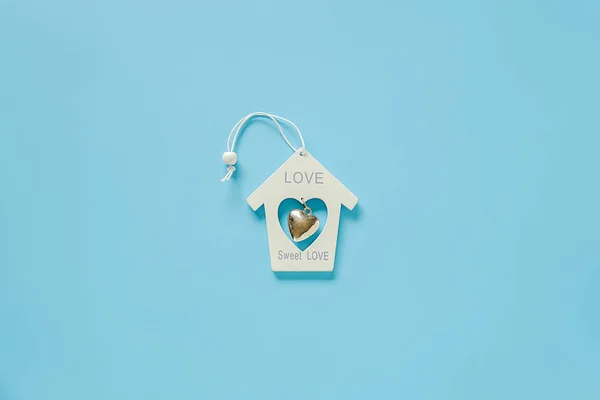 Spielzeughaus aus weißem Holz mit Metallherz auf blauem Hintergrund. Konzept liebe süße Liebe. Kopierraum minimaler Stil Draufsicht flache Layervorlage für Design, Karte, Einladung — Stockfoto