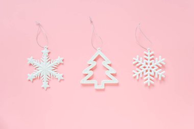 Üç beyaz Noel dekorasyon kar tanesi, pembe arka planda ağaç oyuncak. Konsept Merry Christmas mutlu yeni yıl. Minimal stil üst görünüm düz yatıyordu Kopyala alanı. Tasarım, kart, davetiye için şablon