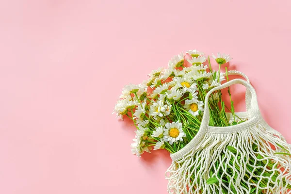 Bouquet of field daisies in reusable shopping eco mesh bag on pink background. Concept no plastic and zero waste. Copy space Top view — Stock Photo, Image