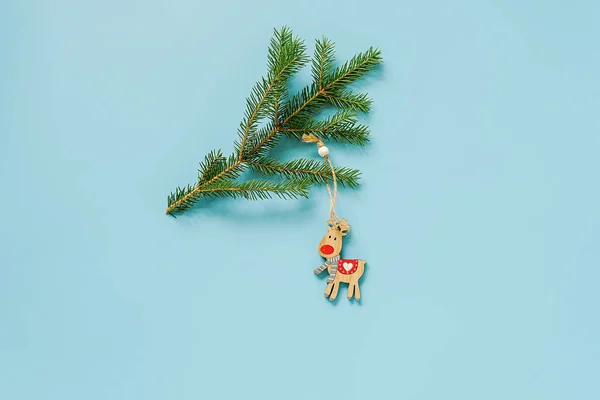 Décoration de Noël jouet de cerf sur branche de sapin sur fond bleu avec espace de copie. Concept Joyeux Noël ou Bonne année. Style minimal Vue de dessus Pose plate Modèle pour la conception, carte, invitation — Photo