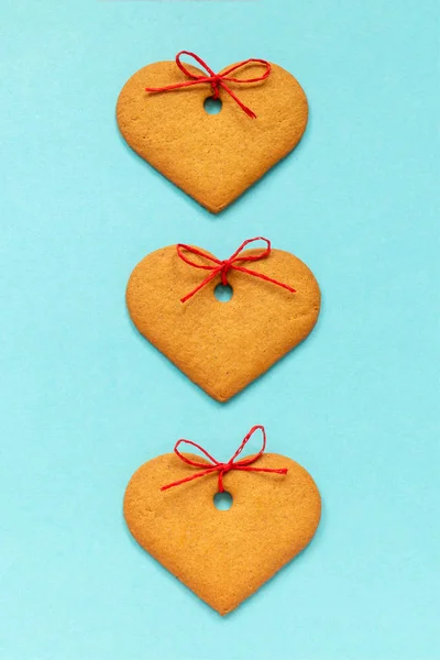 Galletas de jengibre en forma de corazón decoradas con un lazo sobre fondo azul. Vista superior Copiar espacio Tarjeta San Valentín —  Fotos de Stock