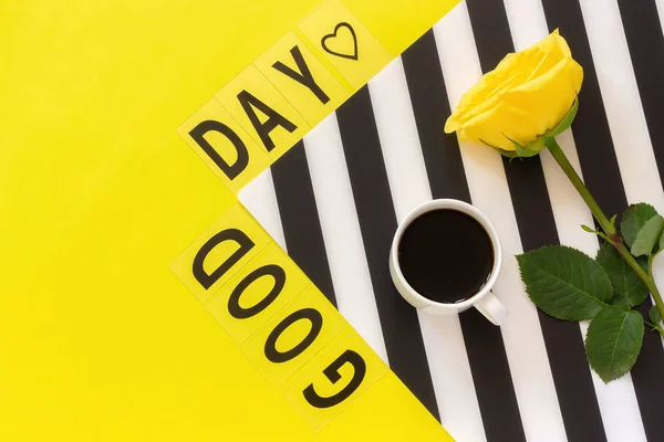 Text Guten Tag, Kaffee und gelbe Rose auf stilvoller schwarz-weißer Serviette auf gelbem Hintergrund. Konzept flach von oben — Stockfoto