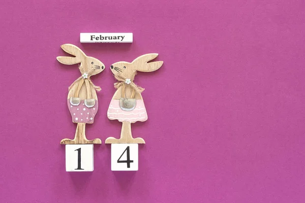 Composición romántica Calendario de cubos de madera 14 de febrero y par de amantes de la madera conejos figurados sobre fondo púrpura. Concepto tarjeta de San Valentín. Vista superior Flat Lay —  Fotos de Stock