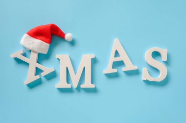 Metin Xmas cilt beyaz harfler ve mavi arka plan üzerinde kırmızı Santa şapka.