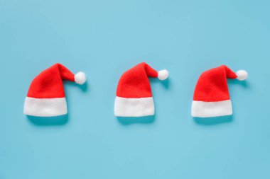Mavi arka planda üç kırmızı Noel Baba şapkası