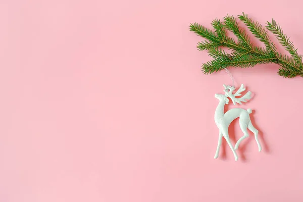 コピースペースとピンクの背景にモミの枝に白いクリスマスの装飾鹿のおもちゃ — ストック写真