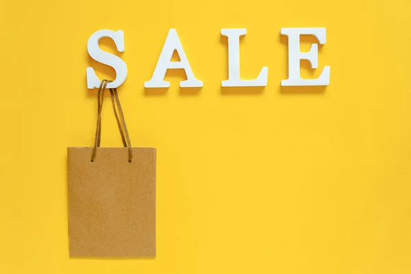 Text SALE from white volume letters and blank shopping bag on yellow background