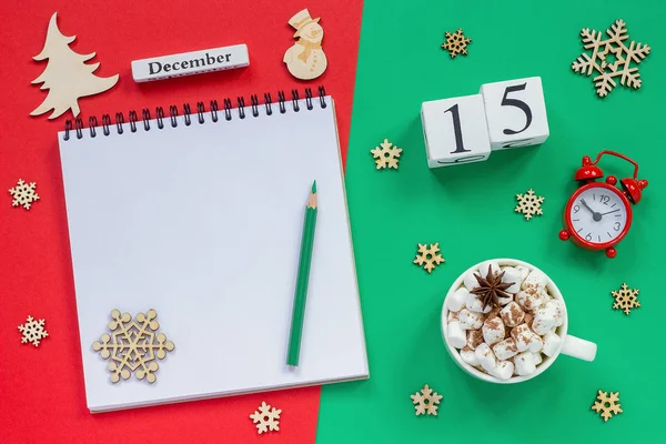 木製のカレンダー12月15日 マシュマロとココアのカップ 赤と緑の背景に目覚まし時計と空のオープンメモ帳 — ストック写真
