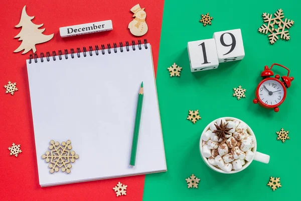 木製のカレンダー12月19日 マシュマロとココアのカップ 赤と緑の背景に目覚まし時計と空のオープンメモ帳 — ストック写真