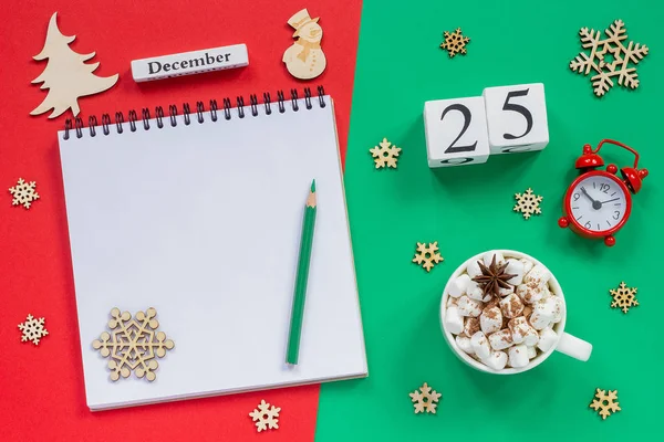 木製のカレンダー12月25日 マシュマロとココアのカップ 赤と緑の背景に目覚まし時計と空のオープンメモ帳 — ストック写真