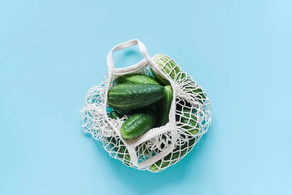 신선한 녹색 오이 야채 재사용 가능한 쇼핑 에코 frendly 메쉬 가방에 푸른 배경에. 개념 은 플라스틱과 제로 폐기물없습니다. 복사 공간 상단 보기 플랫 레이 — 스톡 사진