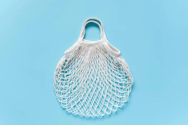 empty white reusable shopping eco mesh bag on blue background. Concept no plastic, zero waste and caring for environment. Copy space Top view Layout for your design