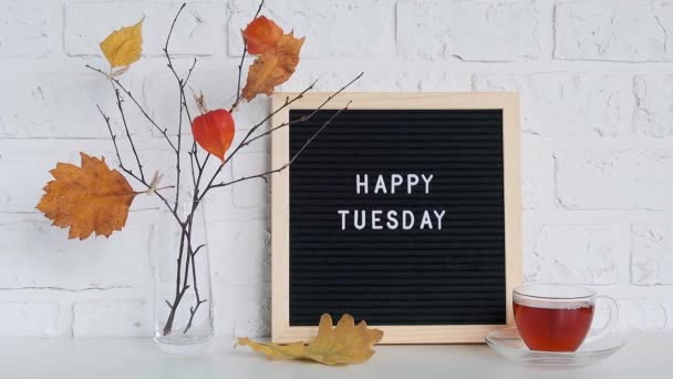 Happy Tuesday text on black letter board and bouquet of branches with yellow leaves on clothespins in vase on table Template for postcard, greeting card Conceito Olá outono Terça-feira — Vídeo de Stock