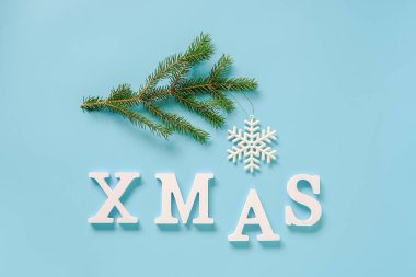 Metin Xmas beyaz harfler ve ladin dalı, mavi arka plan üzerinde noel dekorasyon kar tanesi oyuncak. Konsept Mutlu Noeller. Kopya alanı Üst görünüm Tasarım, kart, davetiye için Düz lay Şablonu