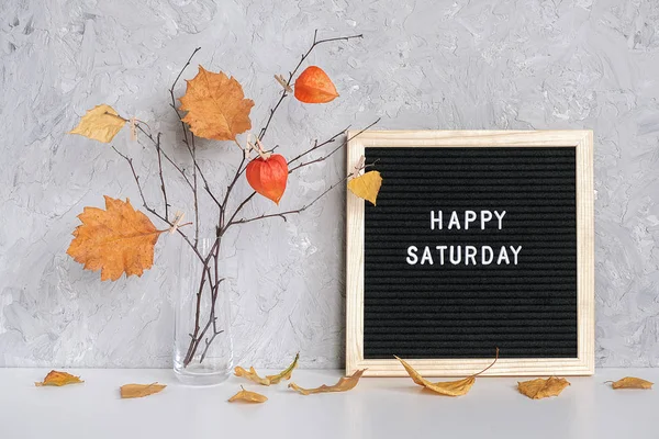 Gelukkig zaterdag tekst op zwarte letter Board en boeket van takken met gele bladeren op wasknijpers in vaas op tabelsjabloon voor briefkaart, wenskaart concept Hello herfst zaterdag — Stockfoto