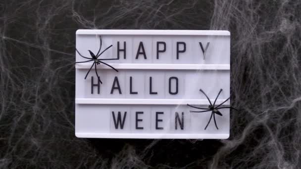 Lightbox met tekst Happy Halloween versierd spinnenwebben en spinnen, close-up. Halloween concept, Top View, platte lay, sjabloon voor wenskaart — Stockvideo