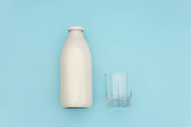 Cam şişede süt ve fotokopi alanı ile mavi arka plan üzerinde boş cam. Düz lay üst görünüm