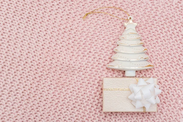 Διακοσμητικό μπεζ χριστουγεννιάτικο δέντρο και κουτί δώρου σε ροζ πλεκτό φόντο. Πρωτοχρονιά ή Χριστουγεννιάτικη ιδέα. Top view Επίπεδο πρότυπο lay για το σχεδιασμό, ευχετήρια κάρτα, πρόσκληση — Φωτογραφία Αρχείου