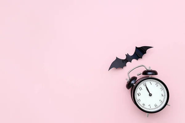 Halloween-Nacht-Konzept. schwarzer Wecker und fliegende Fledermaus auf rosa Hintergrund. kreative flache Lage, Draufsicht, Kopierraum, Vorlage für yuor Design, Grußkarte, Einladung — Stockfoto