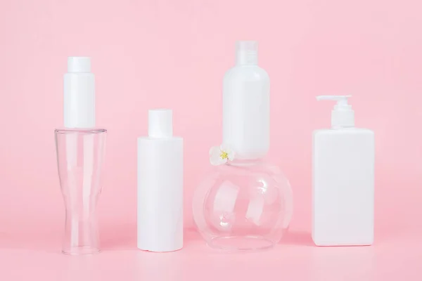 体または髪のためのケア化粧品のセット ガラスのポディウム ピンクの背景に白い空白の化粧品ボトルとチューブ スパコスメティックビューティーコンセプト フロントビュー Mockup — ストック写真