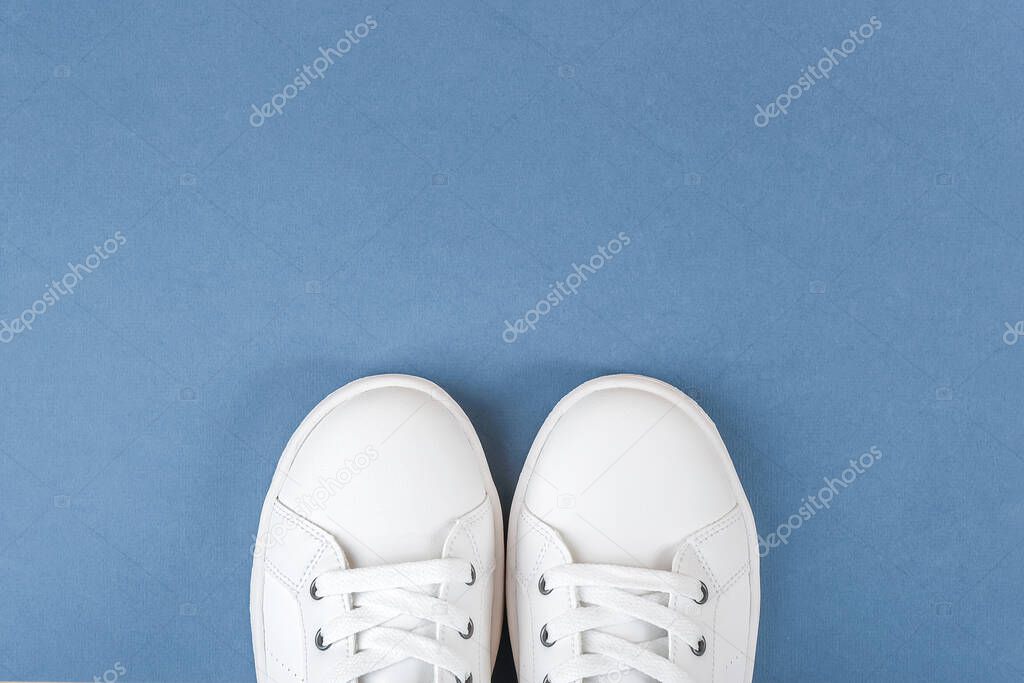 White sports shoes, sneakers with shoelaces on blue background. Sport lifestyle concept Top view Flat lay Copy space.