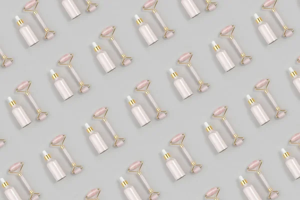 Cosmetic pattern. Crystal rose quartz facial roller and anti-aging collagen, serum in glass bottle on grey background. Facial massage for natural lifting, Beauty concept Top view Flat lay.