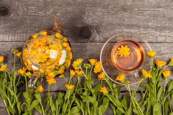 ハーブティーと透明なティーポットと木の背景にマリーゴールドの花のカップ カレンダーティーはあなたの健康の概念を利用する トップ表示 — ストック写真