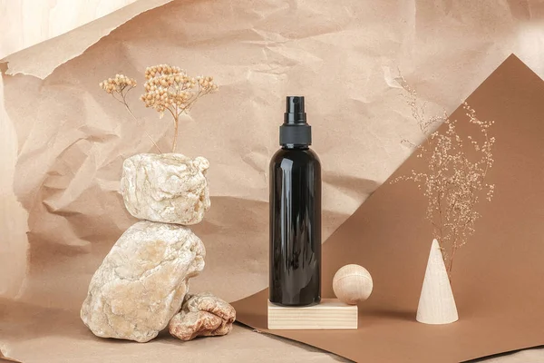 Brown bottle of cosmetic products on stone, wooden geometric shapes on beige paper background. Natural Organic Spa Cosmetic Beauty concept Front view.