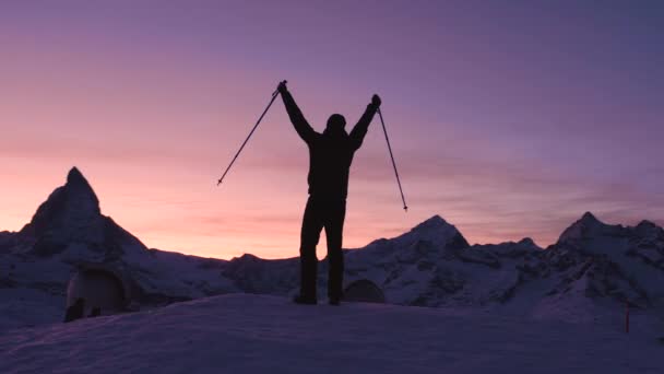 日没時に丘の上に立ちながら ハイキングスティックで手を挙げる男 — ストック動画