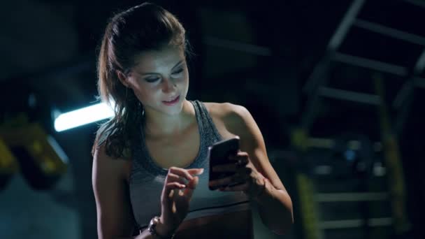 Primer plano Shot of Young Fit Woman en ropa deportiva que sostiene mensajes de texto de teléfono inteligente en interiores Detección de la cara de la aptitud Escaneo 3D Reconocimiento facial biométrico ID Conexiones 5G Futuro tiro rojo épico 8k — Vídeos de Stock