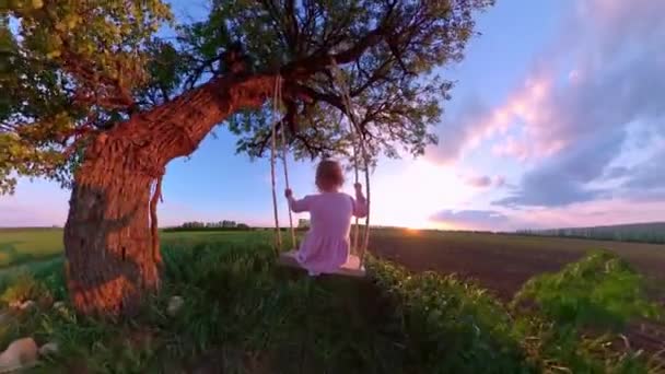 Tahta bir salıncakta oynayan güzel bir kızın altın gün batımına bakan mutlu bir aile görüntüsü 360 Vr kamera ilk kişi yavaş çekim — Stok video