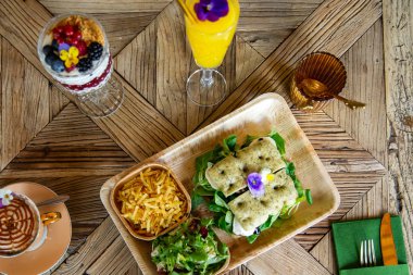 Cappuccino kahve fincanı ve kahvaltı ahşap masada. 