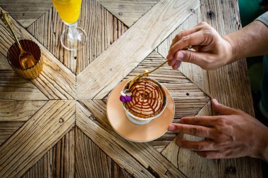 Tahta masada kuponlu ve kapuçino bardaklı bir adam. 
