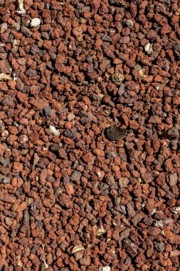 Yerde küçük kırmızı çakıl taşı dokusu var.
