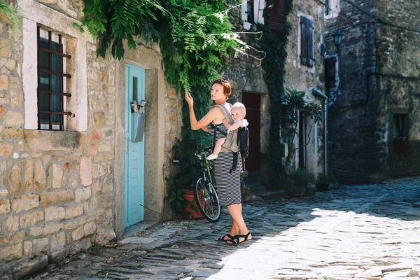 Young woman and baby in historical town of Groznjan, Croatia, Europe. Mother with cute little child on old european street. Typical medieval italian and istrian streets. Family travel Europe